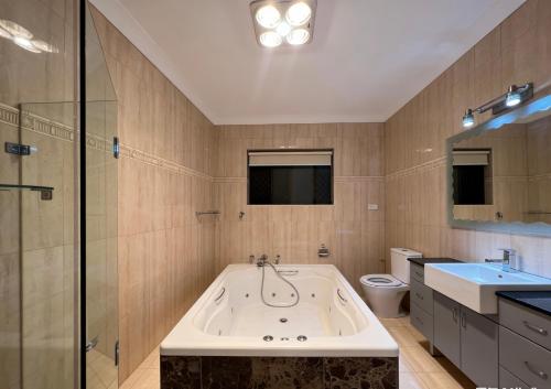 a bathroom with a tub and a toilet and a sink at Burwood central home in Sydney