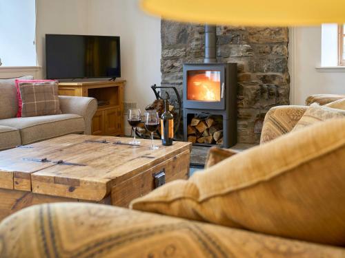 a living room with a fireplace and a table with wine glasses at Weavers Cottage in Kenmore