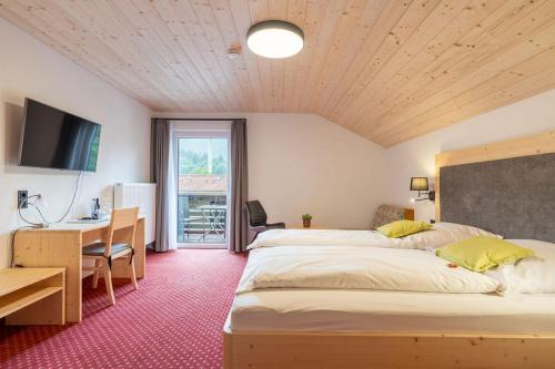 a bedroom with two beds and a desk and a table at Hotel Restaurant Frühlingsgarten in Füssen