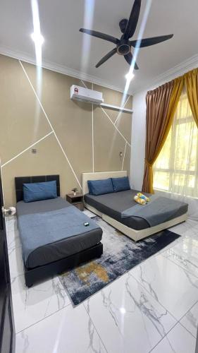 two beds in a room with a ceiling fan at Hijrah De La Villa Parit Buntar Nibong Tebal Penang in Nibung Tebal