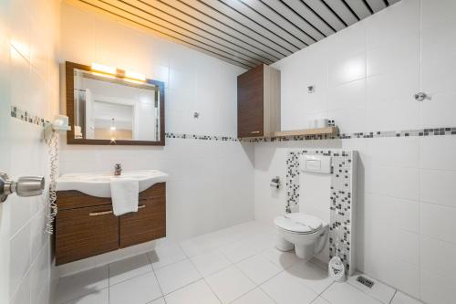 a bathroom with a toilet and a sink and a mirror at Cleopatra Ada Apart & Suites Hotel in Alanya