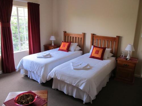 two beds in a hotel room with red curtains at Melody Guest House in Centurion