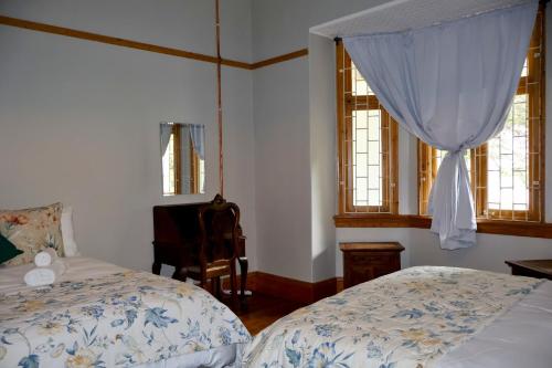 a bedroom with two beds and a chair and windows at The Dullstroom Inn in Dullstroom