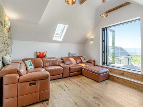 a living room with a leather couch and a large window at Ty Gladys in St. Davids