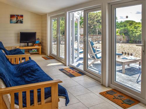 a living room with sliding glass doors and a television at The Seas Beach House in Bacton