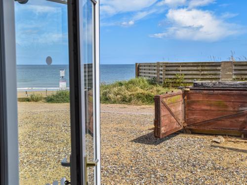 a view of the beach through a glass window at The Seas Beach House in Bacton