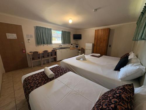 a hotel room with two beds and a kitchen at Mackay Motor Inn in Mackay