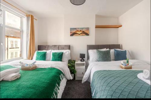a bedroom with two beds with green sheets and a window at Ridley Premium Stay in Leicester
