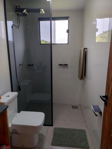 a bathroom with a toilet and a glass shower at Chalé Céu Estrelado in Paraisópolis