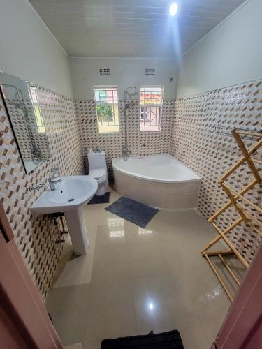 a bathroom with a white tub and a sink at Agreste Homes in Kasama