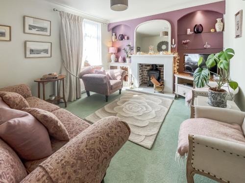a living room with purple walls and a fireplace at Lavender Cottage in Louth