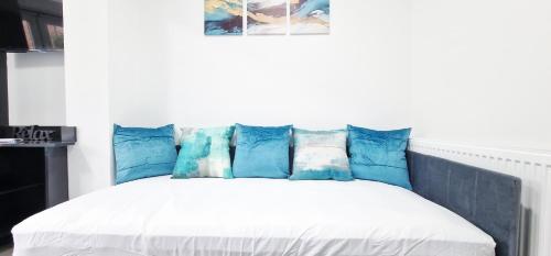 a bed with blue and white pillows on it at Modern Flat Close to Oxford City Centre in Oxford