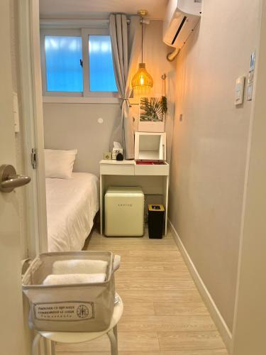 a small room with a bed and a desk and a window at GreeneStay Sindang DDP Seoul in Seoul
