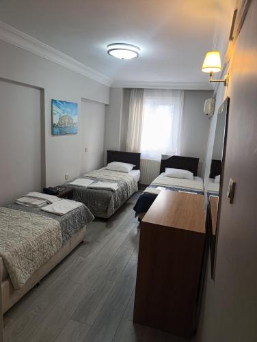 a hotel room with three beds and a window at otel efendi in Istanbul