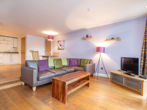 a living room with a couch and a tv at 206 By The Bridge Apartment in Inverness