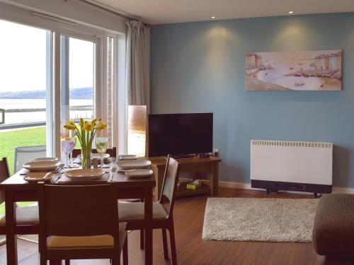 a dining room with a table and a television at Gower Sunset Views in Llanelli