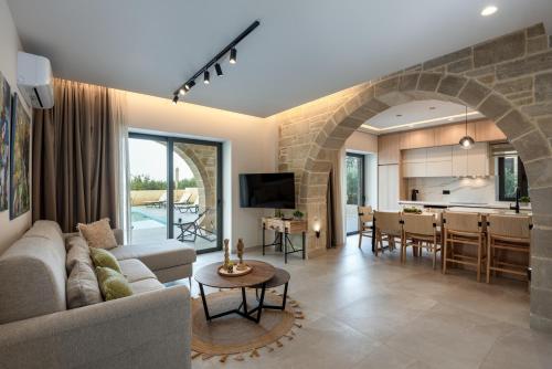 a living room and kitchen with a stone wall at Golden Silence in Platanias