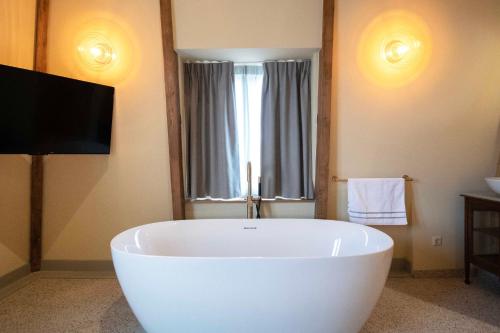 a large white tub in a bathroom with a television at Boetiekhotel Het Gezellenhuis in Ouderkerk aan de Amstel
