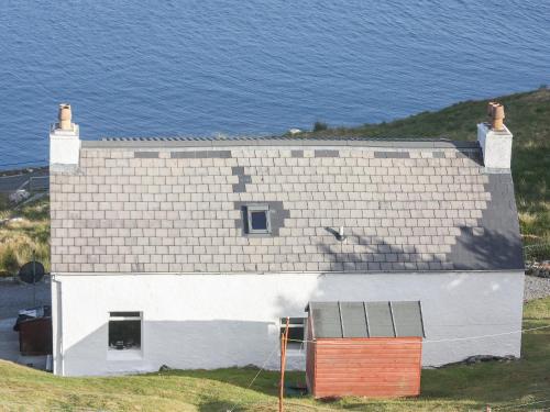 a white house on a hill next to the ocean at Tigh Mairi in Tarbert