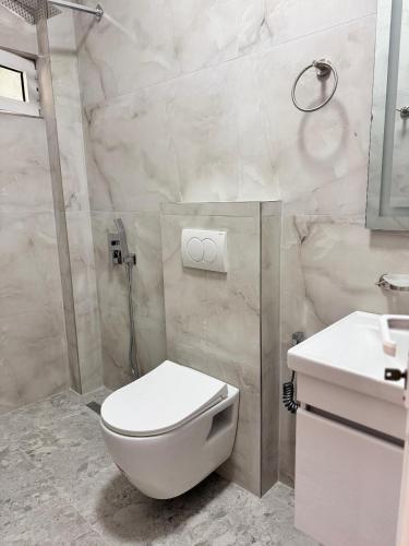 a white bathroom with a toilet and a sink at City & Sea Hideout in Himare