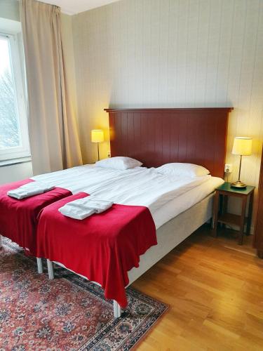 a bedroom with a large bed with a red headboard at Hotel Bishops Arms Kristianstad in Kristianstad