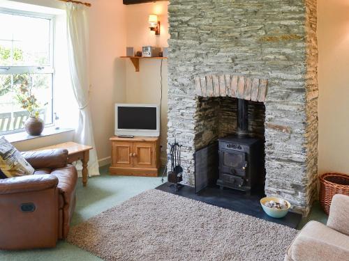 a living room with a stone fireplace and a television at 7 Quarrymans Cottage in Wadebridge