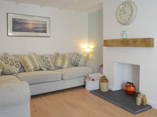 a living room with a couch and a clock on the wall at Snowdrop Cottage in Fishguard