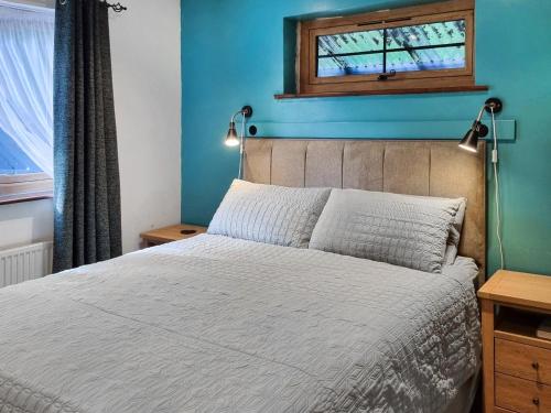 a bedroom with a bed with a blue wall at The Glen in Devils Bridge