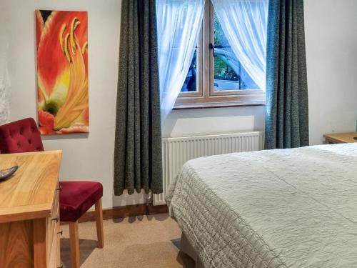 a bedroom with a bed and a desk and a window at The Glen in Devils Bridge