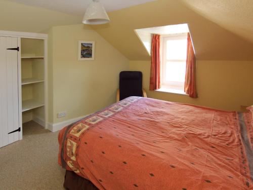 a bedroom with a bed and a window at Ivybank Cottage in Lamlash
