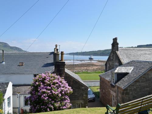 a building with a bush of flowers in front of it at Ivybank Cottage in Lamlash