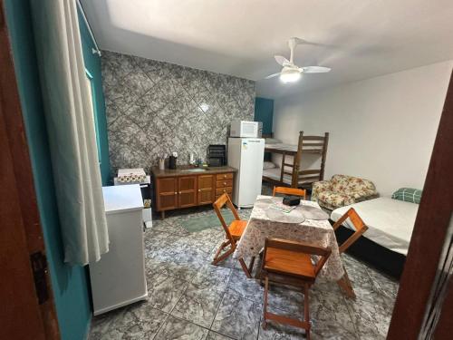 a room with a table and chairs and a kitchen at Kitnet Estrela do Mar in Peruíbe