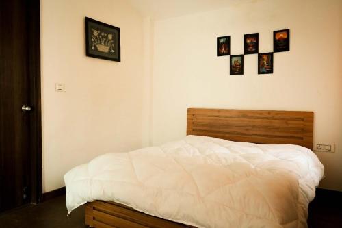 a bedroom with a white bed with pictures on the wall at Echoes of Doon in Rājpur