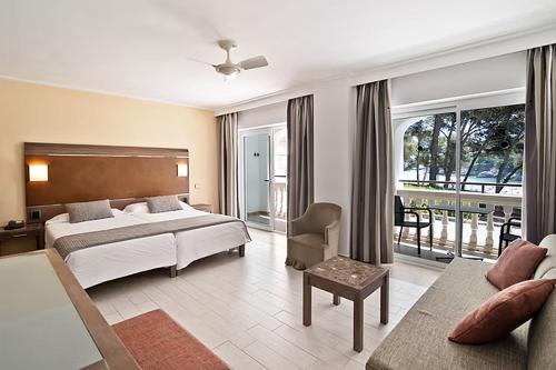 a hotel room with a bed and a couch at FERGUS Club Font de Sa Cala Beach in Capdepera