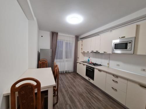 a kitchen with white cabinets and a table and a microwave at Rădăuți Residence 2 in Rădăuţi
