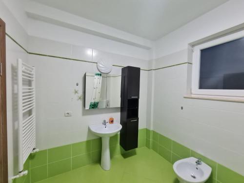 a green and white bathroom with two sinks and a window at Rădăuți Residence 2 in Rădăuţi