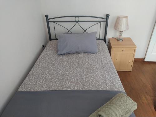 a bed with a gray pillow and a night stand at Spiros old town apartment in Corfu