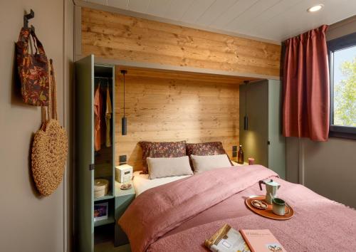 a bedroom with a bed with a wooden wall at VVF Aubrac in Chaudes-Aigues
