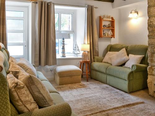 a living room with two green couches and a window at Squirrel Cottage in Filey