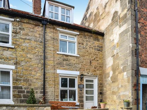 an old brick building with white windows and benches at Squirrel Cottage in Filey