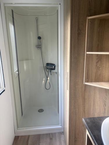 a shower with a glass door in a bathroom at mobilhome 5 personnes in Saint-Arnoult