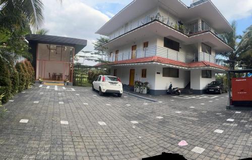 a white car parked in a parking lot in front of a building at MJ paddy view Homestay in Kumarakom