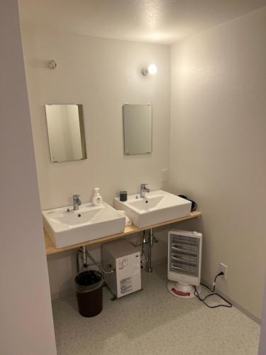 a bathroom with two sinks and two mirrors at Togari Sunshine Lodge in Iiyama