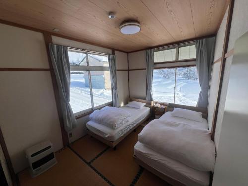 a small room with two beds and two windows at Togari Sunshine Lodge in Iiyama