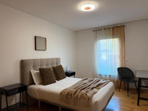 a bedroom with a bed and a chair and a window at Azores Lava Apartment T3 in Ponta Delgada