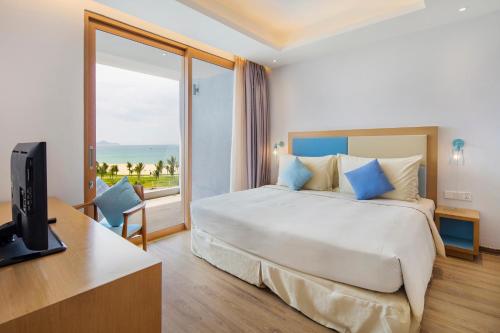 a hotel room with a bed and a desk with a television at FLC Luxury Hotel Quy Nhon in Quy Nhon