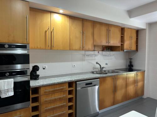 a kitchen with wooden cabinets and a sink at Azores Lava Apartment T3 in Ponta Delgada