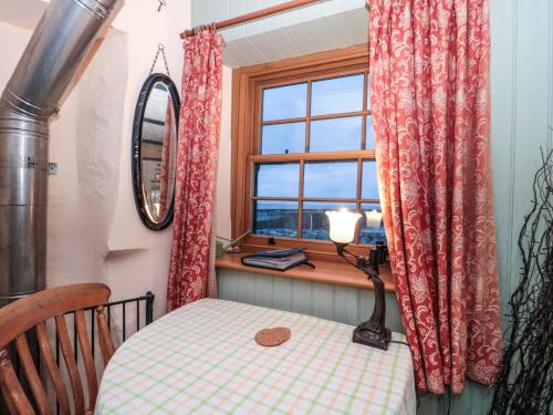 a table and a window in a room with a table and a chair at Sammy Hakes Cottage in Watchet