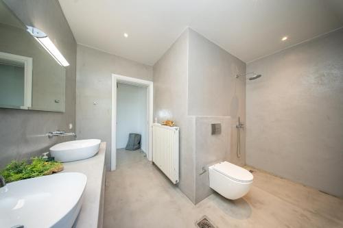 a bathroom with two sinks and a toilet in it at Villa Aionia in Lepeda in Lixouri