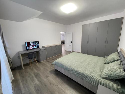 a bedroom with a bed and a desk with a television at Rădăuți Residence 3 in Rădăuţi